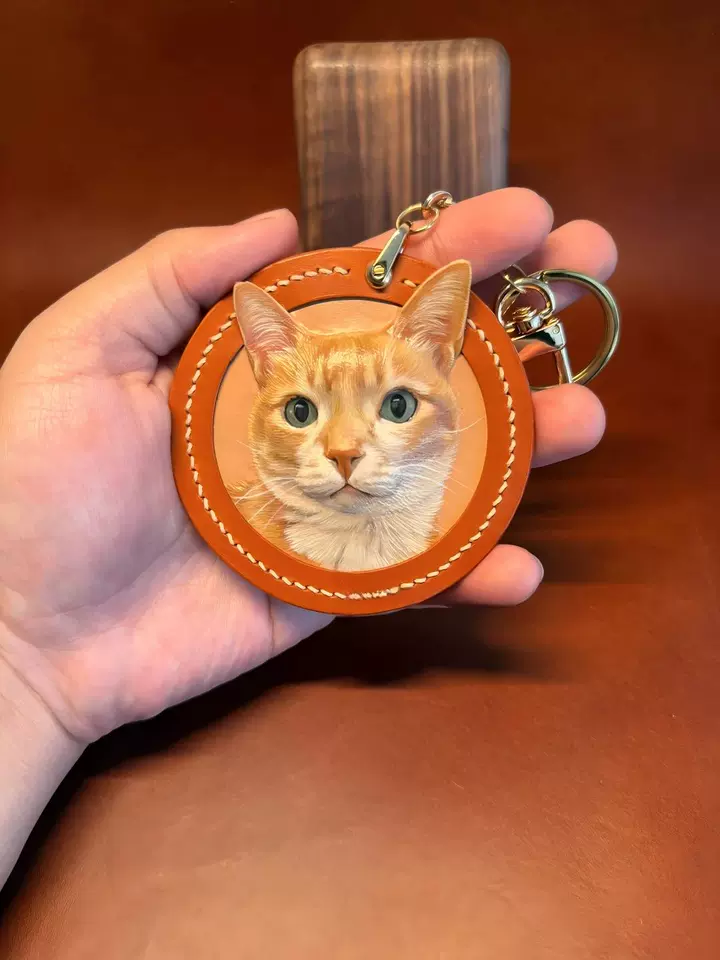 Handmade leather pet portrait charm with a cat portrait.